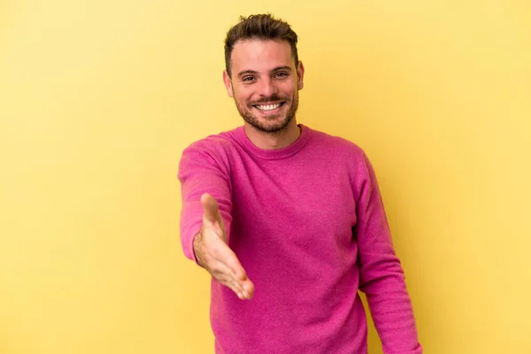 Joven Hombre Caucásico Aislado Sobre Fondo Amarillo Estirando Mano Cámara —  Fotos de Stock