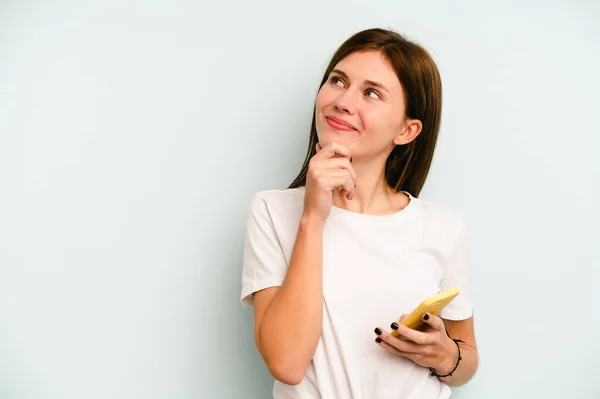 Jonge Engelse Vrouw Houden Mobiele Telefoon Geïsoleerd Blauwe Achtergrond Kijken — Stockfoto