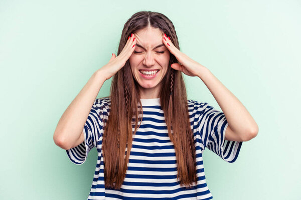 Young caucasian woman isolated on green background touching temples and having headache.