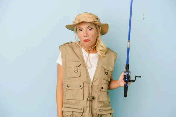 Young Russian Fisherwoman Isolated Blue Background Shrugs Shoulders Open Eyes — Stock Photo, Image