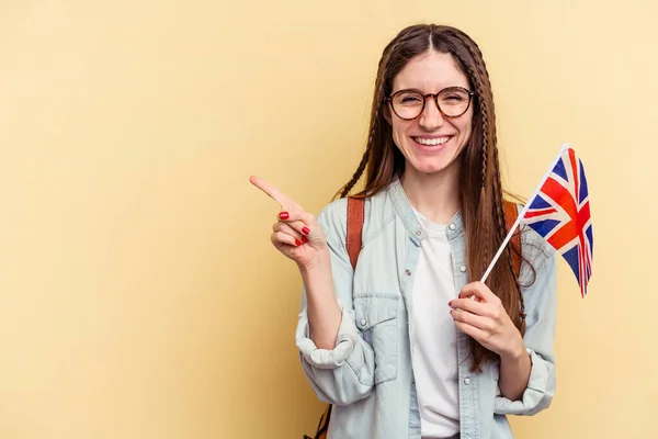 Mladá Běloška Studuje Angličtinu Izolovanou Žlutém Pozadí Usmívá Ukazuje Něco — Stock fotografie