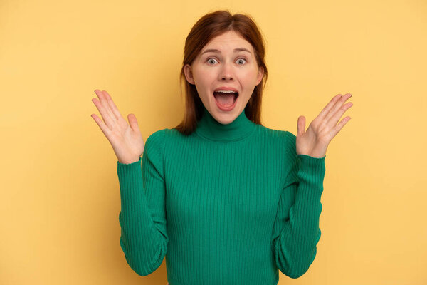 Молодая английская женщина в изоляции на желтом фоне празднуя победу или успех, он удивлен и шокирован.