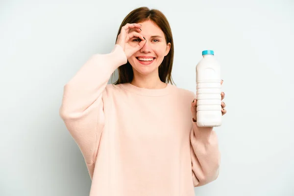 Junge Engländerin Hält Eine Flasche Milch Isoliert Auf Blauem Hintergrund — Stockfoto