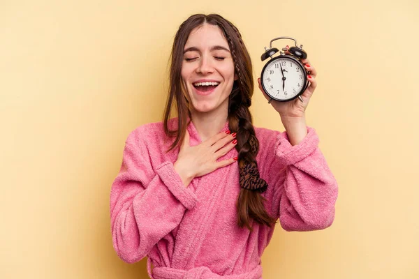 Jovem Caucasiana Vestindo Roupão Banho Segurando Despertador Isolado Fundo Amarelo — Fotografia de Stock