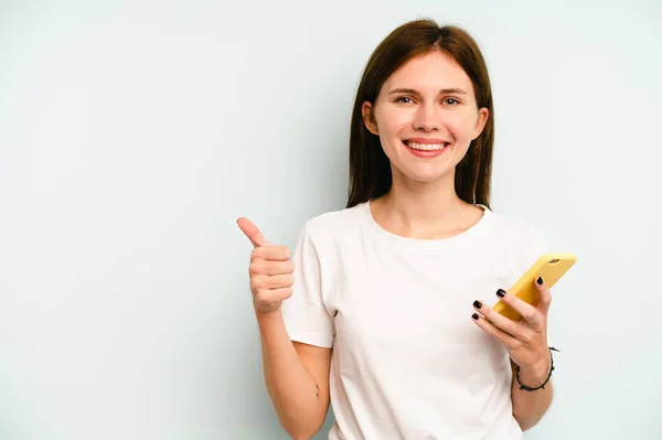 Joven Mujer Inglesa Sosteniendo Teléfono Móvil Aislado Sobre Fondo Azul — Foto de Stock