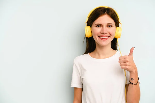 Jong Engels Vrouw Luisteren Naar Muziek Geïsoleerd Blauwe Achtergrond Glimlachen — Stockfoto