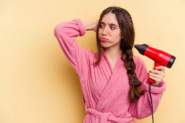 Young Woman Holding Hairdryer Isolated Yellow Background Touching Back Head — Stock Photo, Image