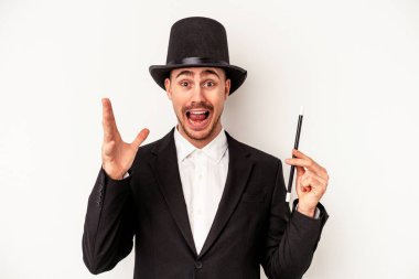 Beyaz arka planda bir değnek tutan genç beyaz büyücü hoş bir sürprizle karşılaşıyor, heyecanlı ve el kaldırıyor..