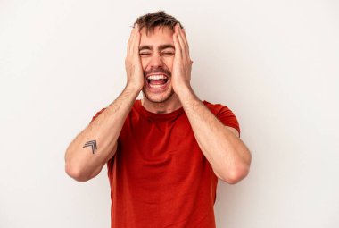 Beyaz arka planda izole edilmiş genç beyaz bir adam kulakları kulaklarıyla kapatıyor ve çok ses duymamaya çalışıyor..