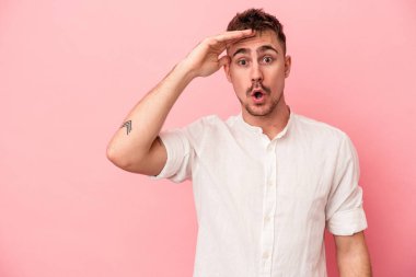 Pembe arka planda izole edilmiş genç beyaz adam yüksek sesle bağırıyor, gözleri açık ve elleri gergin tutuyor..