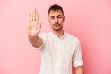 Pembe arka planda izole edilmiş genç beyaz adam elini uzatmış, dur işareti göstererek seni engelliyor..
