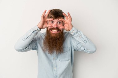 Beyaz arka planda uzun sakallı beyaz tenli genç beyaz adam başarı fırsatı bulmak için gözlerini açık tutuyor..