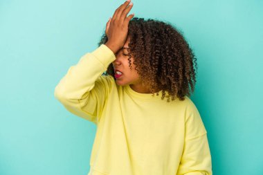 Mavi arka planda yalıtılmış kıvırcık saçlı genç Afro-Amerikalı kadın bir şeyi unutuyor. Alnına avuç içi ve gözlerini kapatarak tokat atıyor..