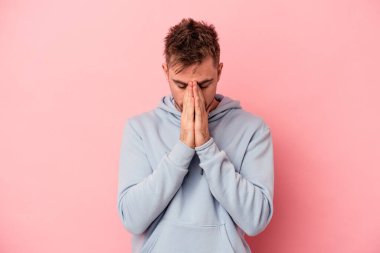 Genç beyaz adam pembe arka planda izole edilmiş dua ediyor, bağlılık gösteriyor, dindar biri ilahi ilham arıyor..