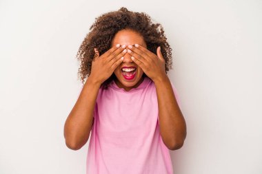 Beyaz arka planda yalıtılmış kıvırcık saçlı, genç Afro-Amerikalı kadın gözleri kaplıyor, gülümseyerek büyük bir sürpriz bekliyor..