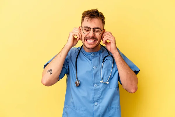 Jonge Verpleegster Kaukasische Man Geïsoleerd Gele Achtergrond Bedekt Oren Met — Stockfoto