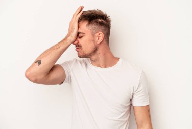 Beyaz arka planda izole edilmiş genç beyaz bir adam işaret parmaklarıyla küçük bir şey tutuyor, gülümsüyor ve kendinden emin..