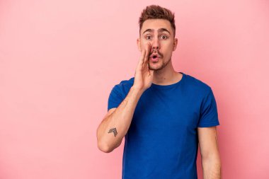 Pembe arka planda izole edilmiş genç beyaz adam gizli bir sıcak fren haberi veriyor ve yana bakıyor.