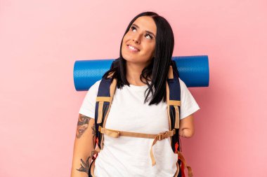 Tek kollu, pembe arka planda izole edilmiş, amaçlarına ve amaçlarına ulaşma hayali kuran beyaz, genç bir yürüyüşçü kadın.