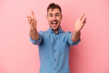 Pembe arka planda izole edilmiş genç beyaz adam kameraya sarıldığı için kendinden emin hissediyor..