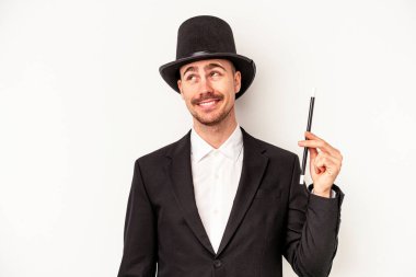 Beyaz arka planda bir değnek tutan Kafkasyalı genç büyücü amaçlarına ve amaçlarına ulaşma hayali kuruyor.