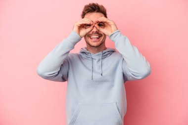 Pembe arka planda izole edilmiş genç beyaz adam gözlerinde sorun olmadığını gösteriyor.