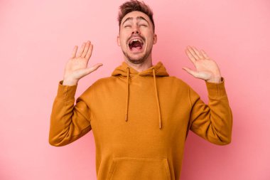 Pembe arka planda izole edilmiş genç beyaz adam gökyüzüne haykırıyor, yukarı bakıyor, hayal kırıklığına uğramış..