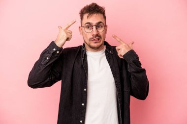 Pembe arka planda izole edilmiş genç beyaz adam işaret parmağıyla hayal kırıklığı jesti gösteriyor..