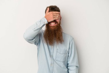 Beyaz arka planda uzun sakallı beyaz tenli genç beyaz adam gözlerini kapar, geniş bir gülümsemeyle bir sürpriz bekler..