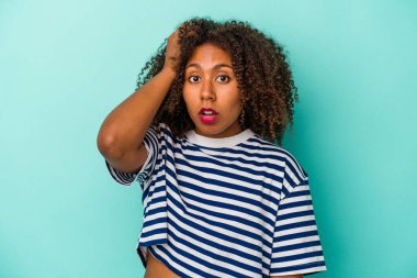Mavi arka planda izole edilmiş kıvırcık saçlı, genç Afrikalı Amerikalı kadın şok geçiriyordu..