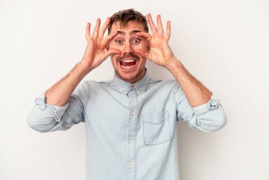 Beyaz arka planda izole edilmiş genç beyaz adam ağzı açık bir şekilde üst tarafı işaret ediyor..