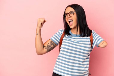 Tek kolu pembe arka planda izole genç beyaz kadın zafer kazandıktan sonra yumruk kaldırıyor, kazanan konsept..