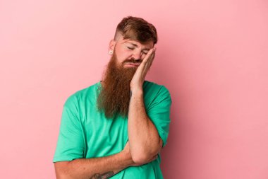 Pembe arka planda uzun sakallı beyaz, genç bir adam. Sıkılmış, yorgun ve dinlenmeye ihtiyacı var..