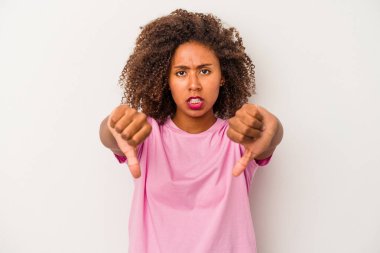 Beyaz arka planda izole edilmiş kıvırcık saçlı genç Afrikalı Amerikalı kadın baş parmağını aşağı gösteriyor ve hoşlanmadığını ifade ediyor..