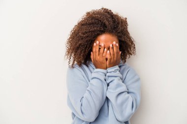 Beyaz arka planda izole edilmiş kıvırcık saçlı, genç Afrikalı Amerikalı kadın kameraya parmaklarıyla göz kırpıyor, yüzünü kapatmaktan utanıyor..