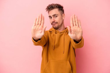 Pembe arka planda izole edilmiş genç beyaz adam elini uzatmış, dur işareti göstererek seni engelliyor..