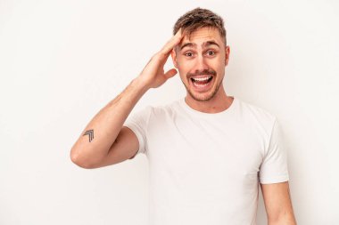 Beyaz arka planda izole edilmiş genç beyaz bir adam iki parmağını da kaldırıyor, gülümsüyor ve kendinden emin..