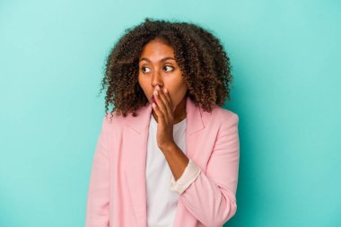 Mavi arka planda izole edilmiş kıvırcık saçlı genç Afro-Amerikalı kadın gördüğü bir şey yüzünden şoka uğruyor..