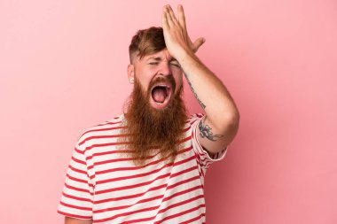 Uzun sakallı beyaz bir adam pembe arka planda bir şeyi unutuyor. Alnına avuç içi ve kapalı gözlerle vuruyor..