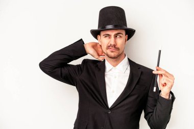 Kafkas büyücüsü beyaz arka planda bir değnek tutuyor. Kafasının arkasına dokunuyor, düşünüyor ve bir seçim yapıyor..