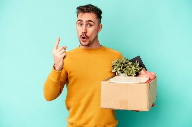 Kafkasyalı genç adam mavi arka planda izole edilmiş bir hareket yapıyor. Bir fikri var, ilham verici bir kavram..