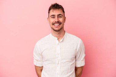 Pembe arka planda izole edilmiş genç beyaz adam mutlu, güler yüzlü ve neşeli.