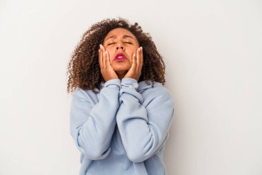 Beyaz arka planda yalnız başına sızlanan ve ağlayan kıvırcık saçlı Afro-Amerikalı genç bir kadın..
