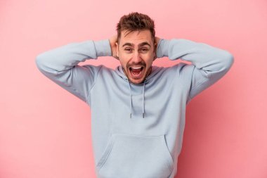 Pembe arka planda izole edilmiş genç beyaz bir adam çığlık atıyor, çok heyecanlı, tutkulu, bir şeyden memnun..