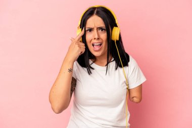 Tek kollu, pembe arka planda izole edilmiş müzik dinleyen beyaz bir kadın işaret parmağıyla yaptığı hayal kırıklığı jestini gösteriyor..