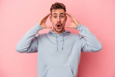 Pembe arka planda izole edilmiş genç beyaz adam hoş bir sürpriz alıyor, heyecanlı ve el kaldırıyor..