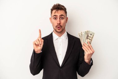 Kafkasyalı genç iş adamı elinde banknotlar tutarak beyaz arka planda izole edilmiş harika bir fikre, yaratıcılık kavramına sahip..