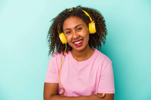 Junge Afroamerikanerin Hört Isoliert Musik Auf Blauem Hintergrund Lacht Und — Stockfoto