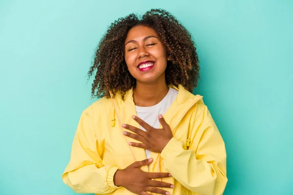 青い背景で孤立した巻き毛の若いアフリカ系アメリカ人女性は喜んで笑い 胃の上に手を保つ楽しみを持っています — ストック写真
