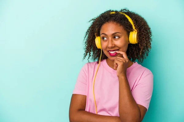 Jovem Afro Americana Ouvindo Música Isolada Fundo Azul Relaxado Pensando — Fotografia de Stock